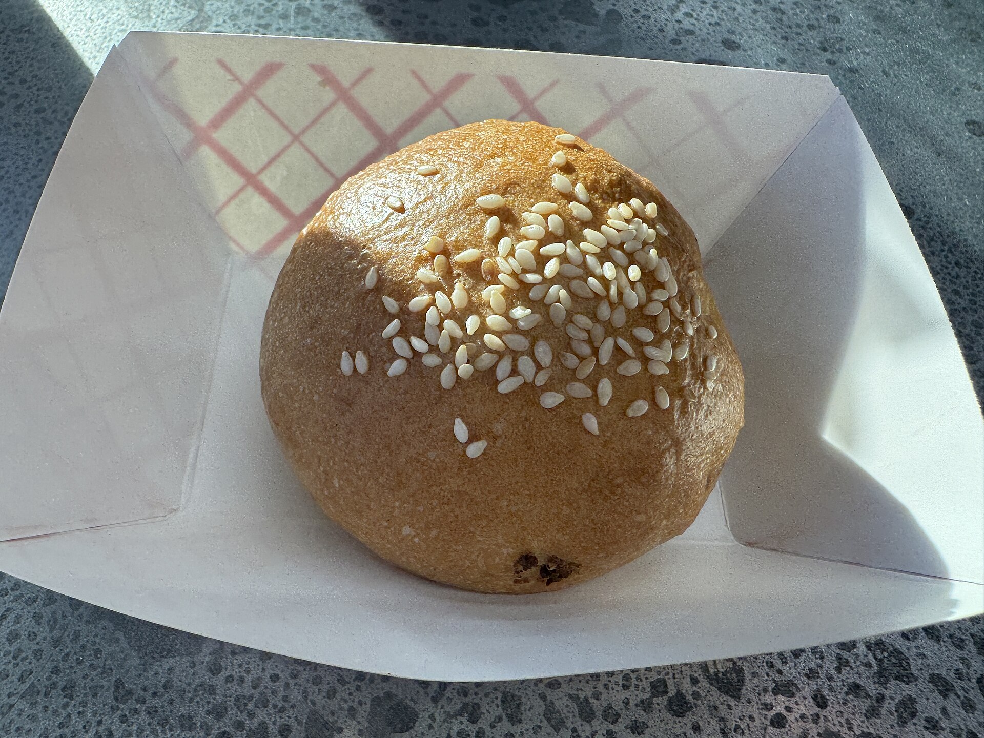 A cheeseburger kolache on a plate at Leo's Market and Eatery in Indianapolis, showing its pastry shell and filling.