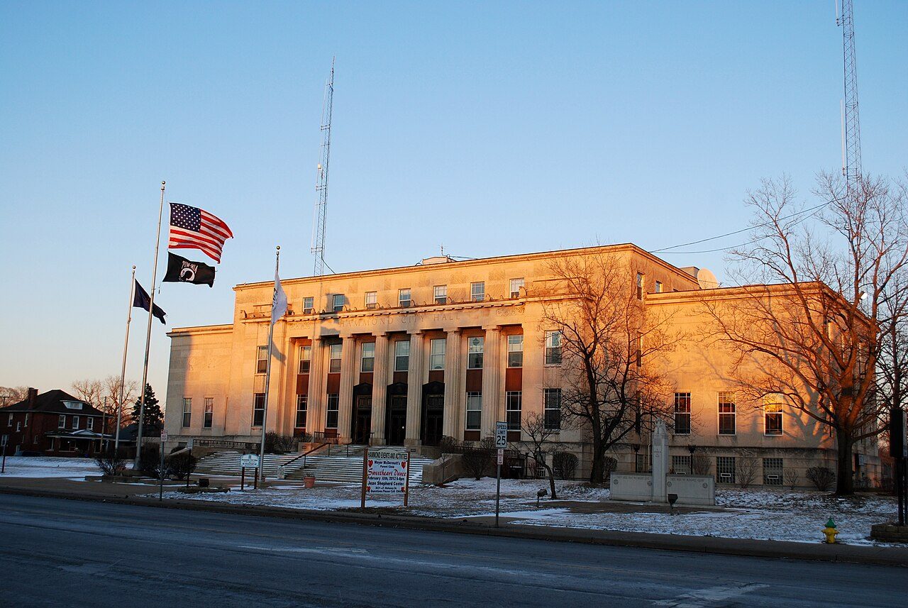 Hammond City Hall limestone facade with columns, flags and a speed-limit sign at golden hour