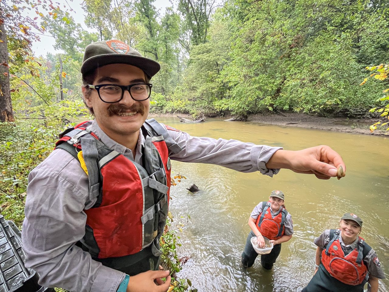 National Park Service staff in red life vests prepare to release mussels in the Little Calumet River