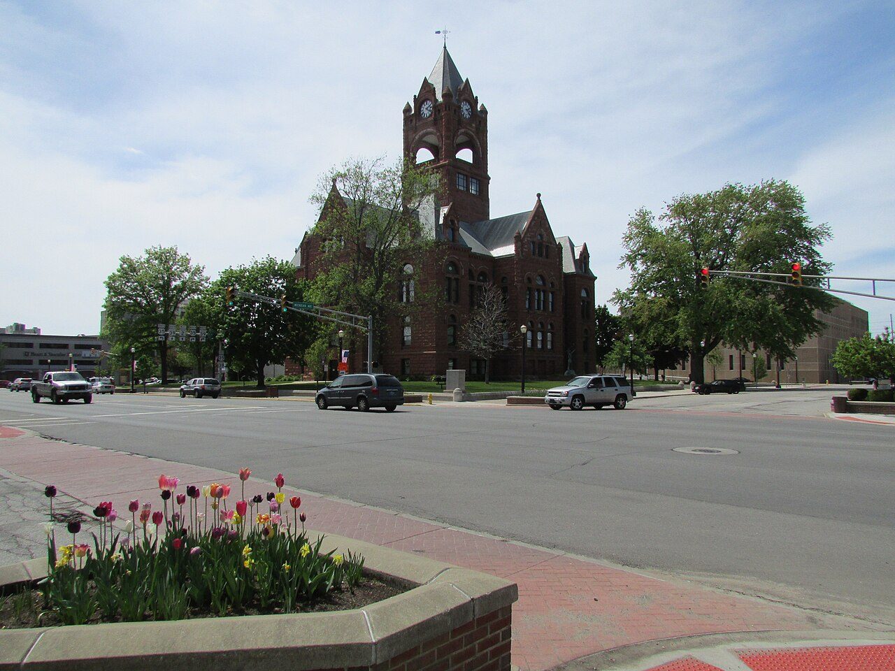 LaPorte County Courthouse clock tower and red-brick facade at a downtown intersection with spring flowers