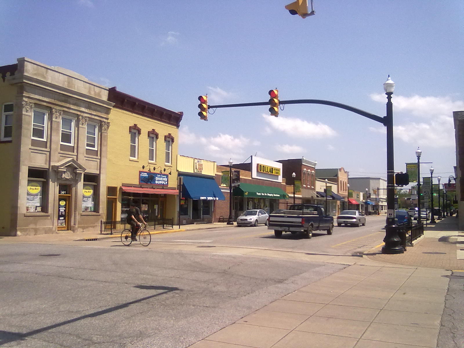 Two-lane Main Street in downtown Hobart lined with brick storefronts under a partly cloudy sky