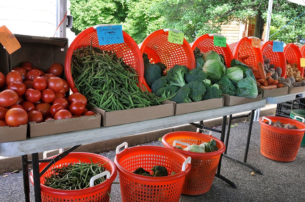 Orange baskets of green beans, broccoli and other vegetables on tables at a farmers market (illustrative file photo)