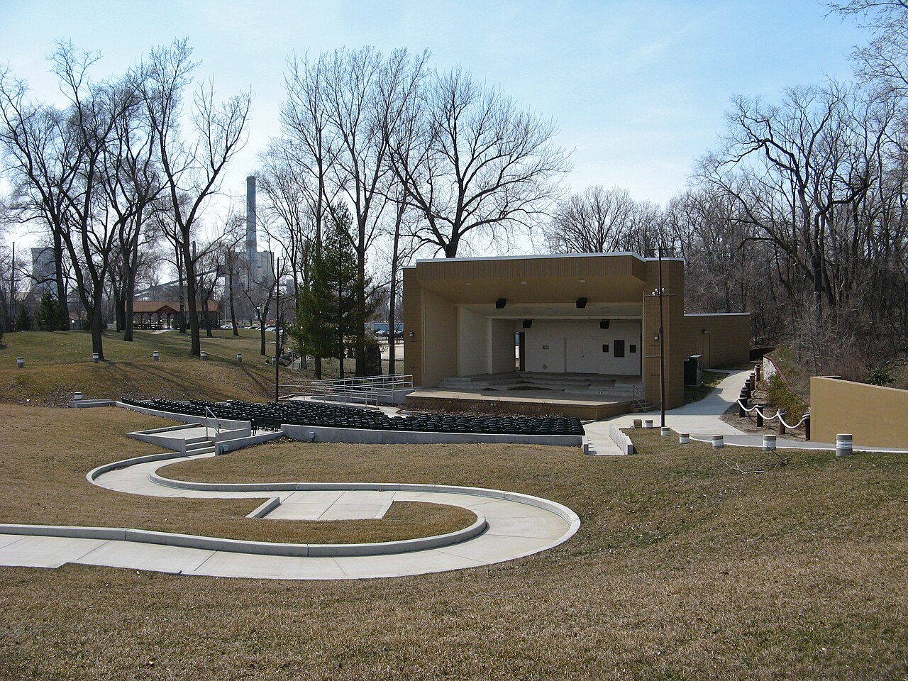 Open-air amphitheater stage and lawn seating at Washington Park in Michigan City under bare early-spring trees